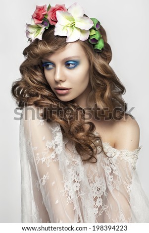 beautiful young woman with fashion make-up, long curly hair and flowers in her hair. Fashion bride