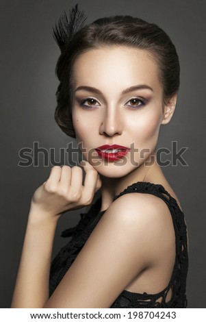 Beautiful young woman with evening makeup on dark background. Vintage retro style woman with red lips and feather