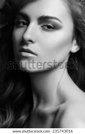 Beautiful young woman with evening make-up and long wavy hair . Smoky eyes. Black and white  photo