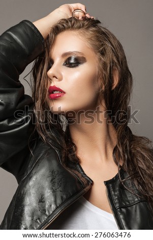 Beautiful young model with fashion makeup and long wet hair. Black smoky eyes and red lips. Rockstar makeup