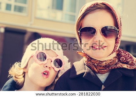 Little girls (sisters) in a headscarf and sunglasses. The image is tinted.