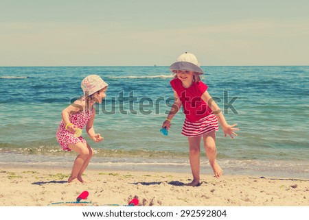 Funny little girls (sisters) play badminton on the beach. The image is tinted.