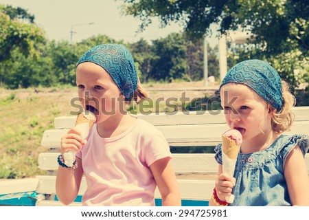 Little cute girls (sisters) eat ice cream, selective focus.