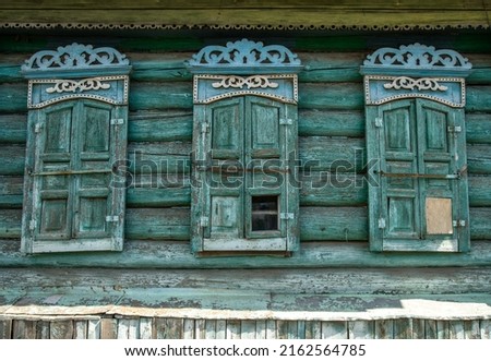 Wall of an old dilapidated log house with three closed windows. Carved platbands and dilapidated shutters Photo stock © 