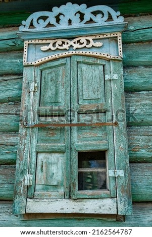 Wall of an old dilapidated log house with a closed window. Carved platbands and dilapidated shutters Photo stock © 