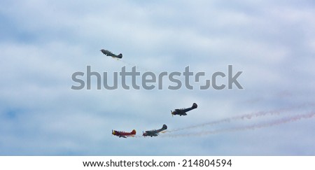 Coruna, Spain - July 17, 2014: Four planes model Yak-52 flying down in formation under a cloudy sky and leaving a smoke trail.