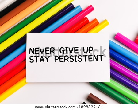 Text NEVER GIVE UP STAY PERSISTENT on paper note with colorful pencils isolated on white background.Motivational quote. 商業照片 © 