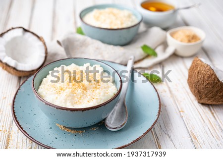 Sweet and creamy coconut rice pudding with honey, topped with grated and toasted coconut in a ceramic bowl Photo stock © 
