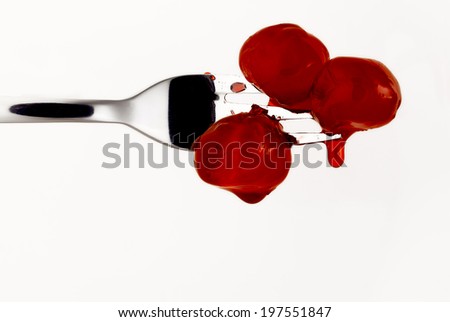 red cherries on a silver fork with syrup drops.