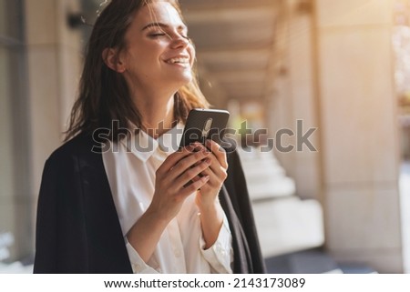 Business woman having good news from partners wia smartphone while walking near office building, Smiling girl chatting with friends while coffee break outdoor Zdjęcia stock © 