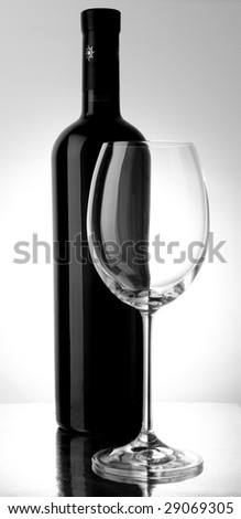 A close wine bottle and glass in a mirror