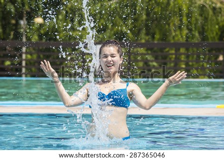 Sexy girl splashing water inside swimming pool and having fun. Happy busty woman with blue swimwear screaming inside pool.