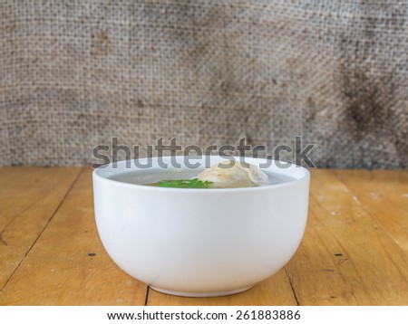 Chicken broth in cup on wooden table