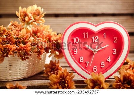 Watch red hearts and flowers in a basket placed on a wooden background. (For a happy time And home decor)