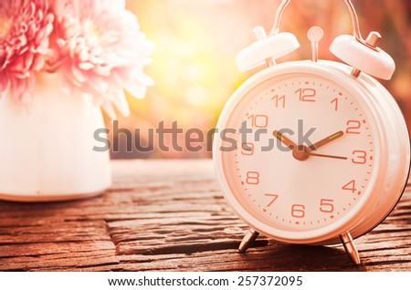 Vintage background.flowers with retro alarm clock on wooden table. black and white