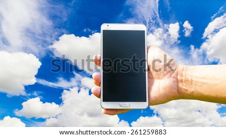Man hand holding smartphone on blue sky background soft focus.