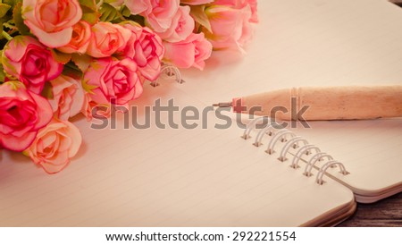 Vintage,retro of note book paper and pen with rose on wooden background soft focus.