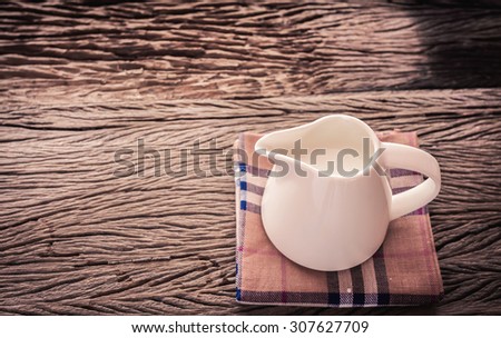 Fresh milk in a jug on wooden background in vintage style soft focus.