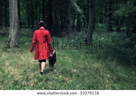 A woman with a red coat and a case is walking in the forest