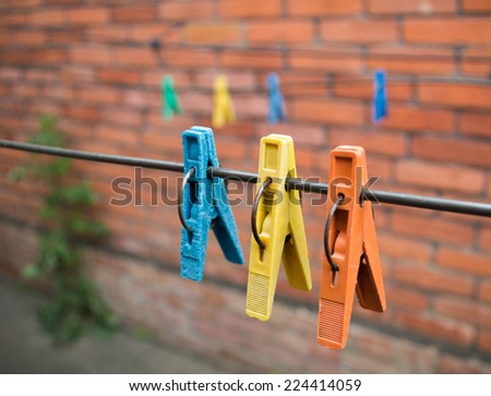 Old clothespins hanging on an iron wire in the background of the red brick wall.