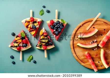 Watermelon pizza bar on blue table. Watermelon with assorti of berries, fruits and ricotta cheese. Pieces of watermelon with kiwi, blueberries, raspberries, apricots and orange on wooden board Photo stock © 