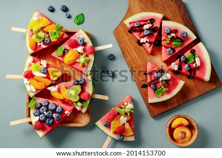 Watermelon pizza bar on blue table. Watermelon with assorti of berries, fruits and ricotta cheese. Pieces of watermelon with kiwi, blueberries, raspberries, apricots and orange on wooden board. Photo stock © 