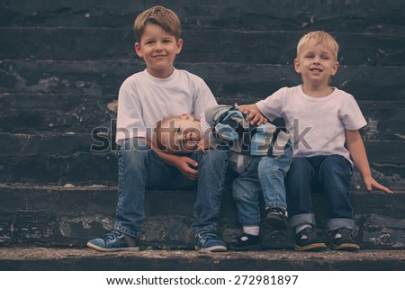 Little brother embracing with the brothers while sitting on a bench
