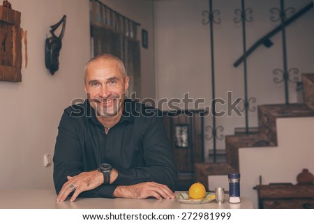 Happy mature man  enjoying drinking tequila  in  kitchen of own house, toned image