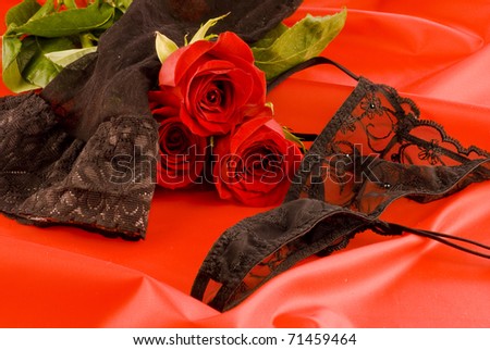Black strings and stockings with red roses on red background