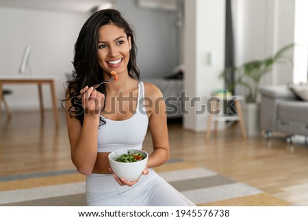Young woman eating a healthy salad after workout. Fitness and healthy lifestyle concept.