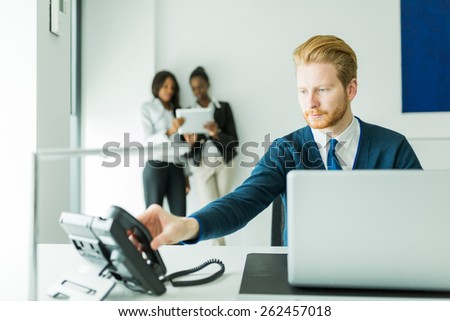 Businessman about to answer the phone with two beautiful,  young women having a conversation in the background