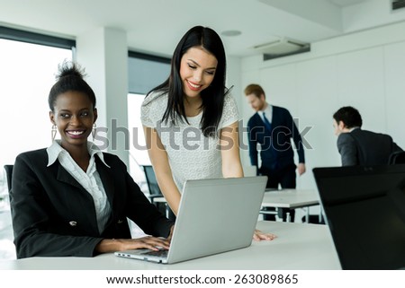 Black and white businesswomen looking at a laptop and working in a neat office environment