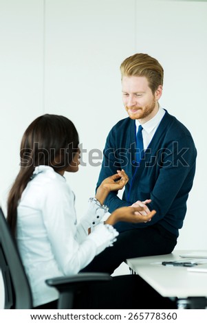 Exchange of thoughts during business meeting break as the businessman sits on the desk and listens to the thought process of the black woman