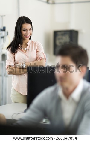Beautiful young female teacher overseeing students\' work in a classrom equipped with computers