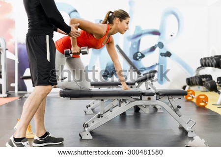 Young male trainer giving instructions to a woman in a gym and being supportive