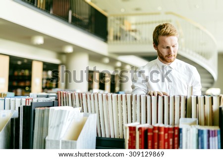 Handsome student searching for a book in a beautiful library