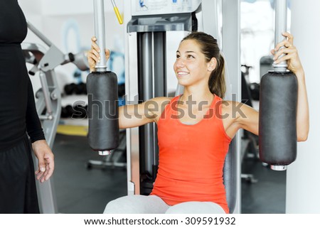 Young male trainer giving instructions to a woman in a gym and being supportive
