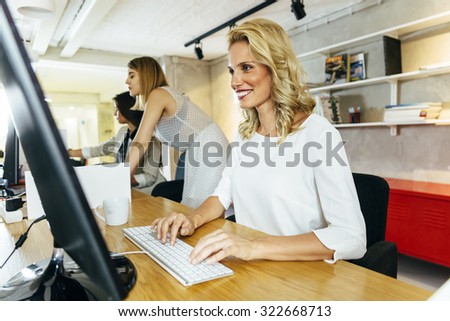 Beautiful woman working in a modern office while sitting in front of a desktop