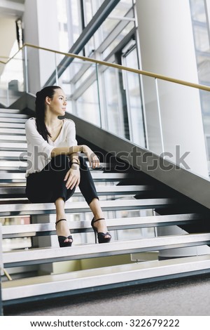 Businesswoman sitting on stairs and thinking. Fashion style photo