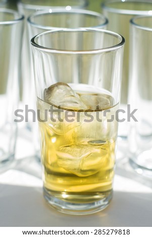 Glass of apple juice with ice. Glasses of sweet carbonated drinks with ice cubes. Whisky on the rocks