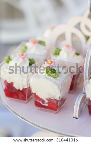 Small cakes with different stuffing. Many tiny cakes with strawberry, coffee, whipped cream, jelly and mint