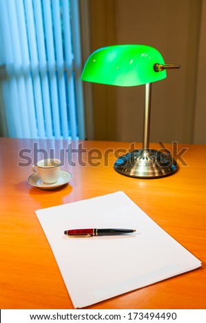 Still life with green lamp cup of coffee pen and paper in the advocate office