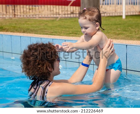 1.5-3 Years little girl swims in  clean water of pool with mom. Concepts and ideas of healthy lifestyle. Facial expression of happy little girl, while floating on water. Summer time on North Israel.