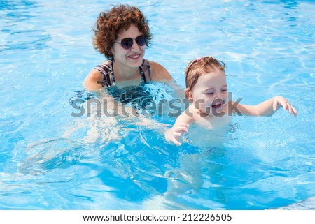 1.5-3 Years little girl swims in  clean water of pool with mom. Concepts and ideas of healthy lifestyle. Facial expression of happy little girl, while floating on water. Summer time on North Israel.