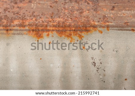 Rusted metal pipe with cracked paint and signs of wear and water stains.