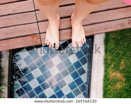 View of bare feet at canal side in the garden