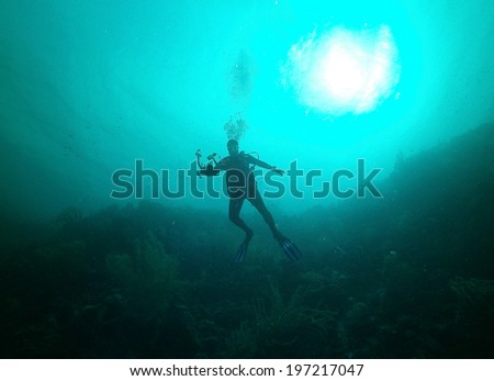 Wide angle shot of SCUBA diver with camera in deep water with Snell\'s Window at Karpata Dive Site in Bonaire, Netherlands Antilles