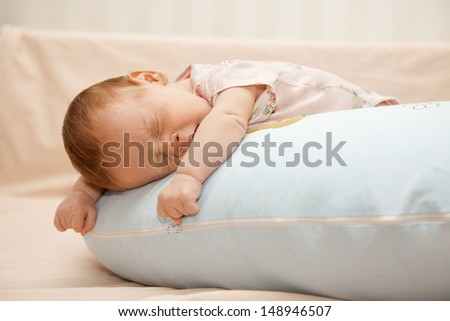 Newborn baby laying on the pillow on his tummy and yawning