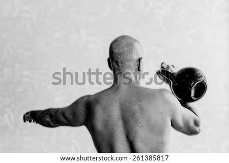 Back view of man doing exercises with kettlebell background. Black-and-white, lite blur background, horizontal