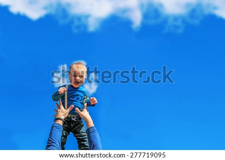 Cute baby boy is being thrown up like little angel is falling from he sky and arms are catching him.